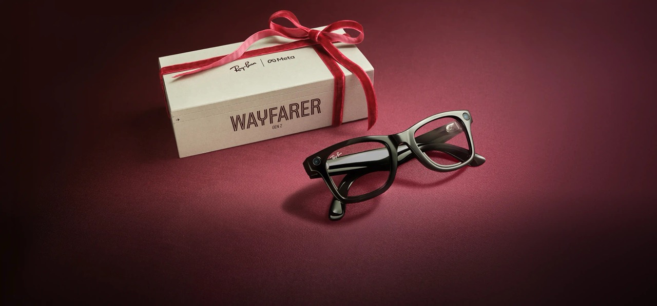 Čierne okuliare Ray-Ban Wayfarer Gen 2 vedľa darčekovej krabičky s červenou stuhou.