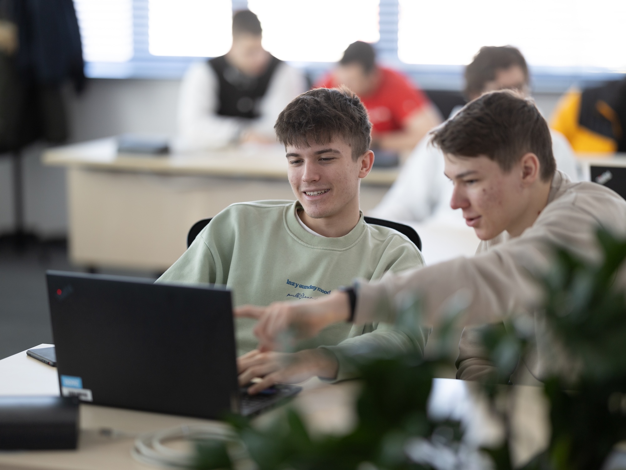 Dva študenti spolupracujú pri počítači v modernom učebnom prostredí.